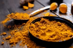 Cúrcuma en polvo y raíz junto a pimienta negra, especias naturales antiinflamatorias para la diabetes